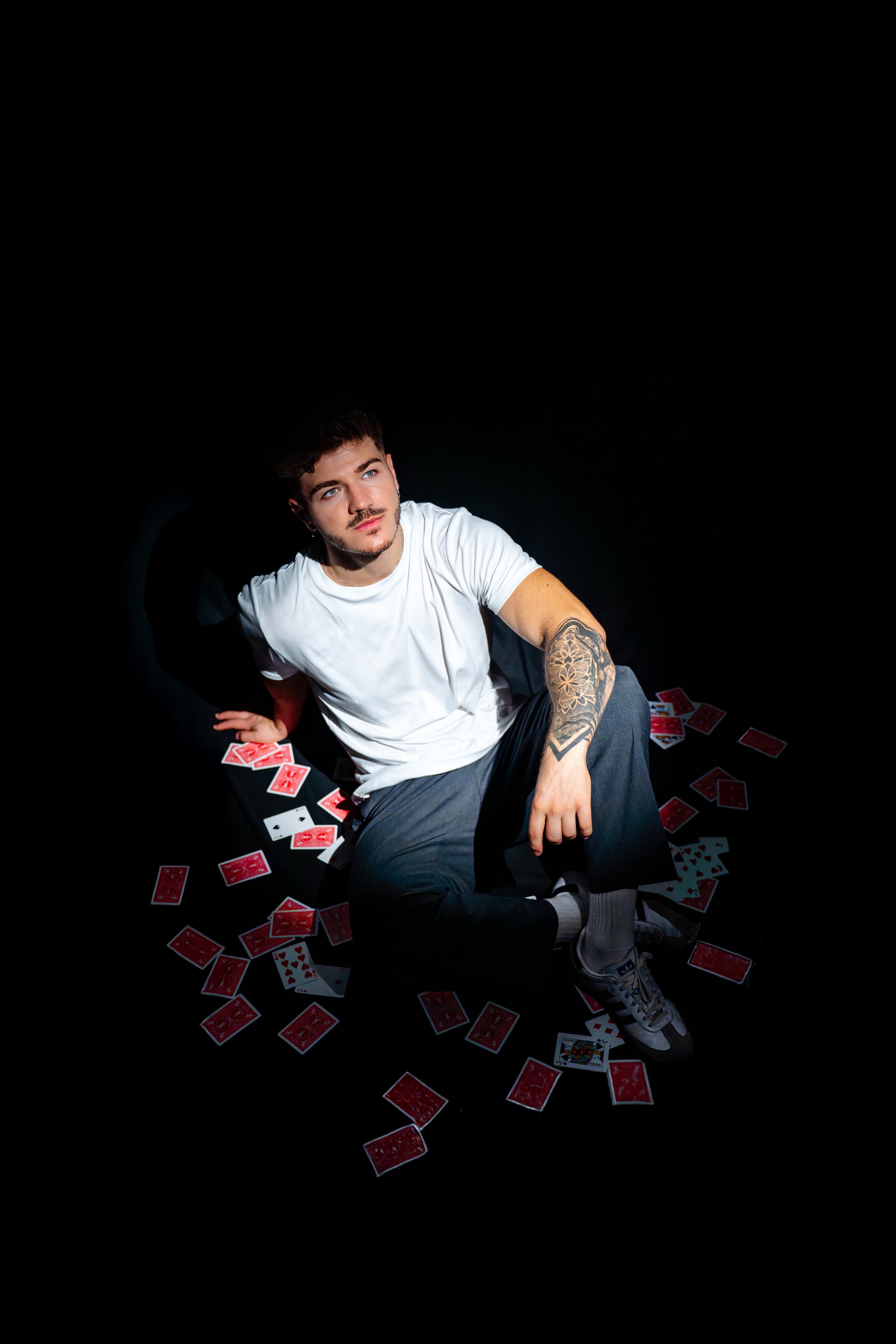 Pando el Mago, rodeado de cartas, con una baraja en la mano