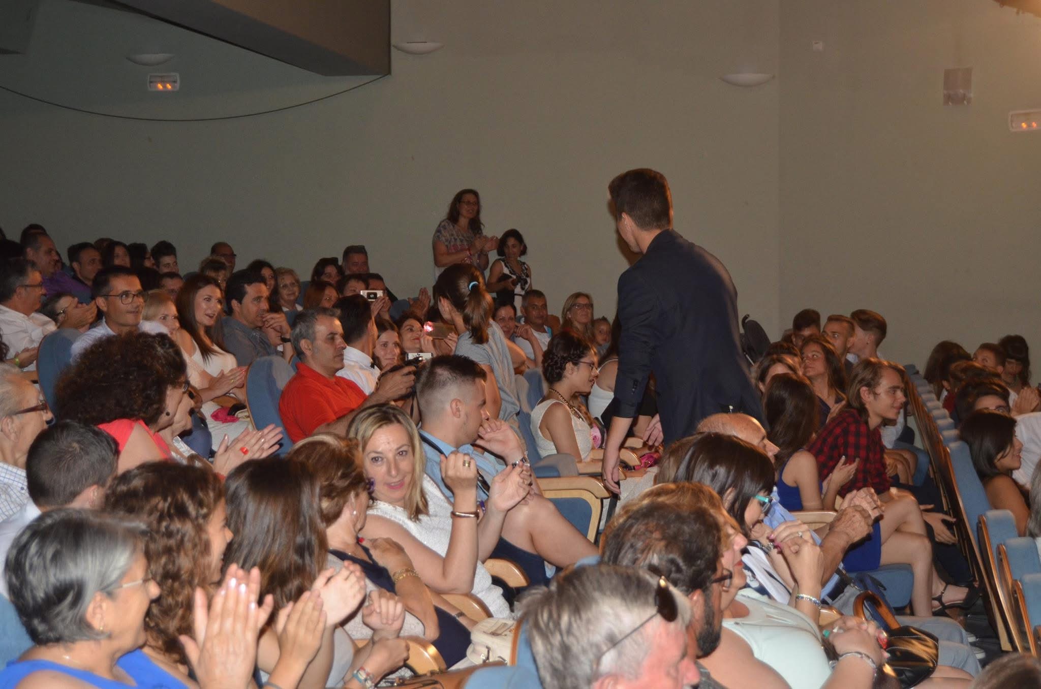 Platea llena de público aplaudiendo mientras Pando el Mago recorre el pasillo del teatro